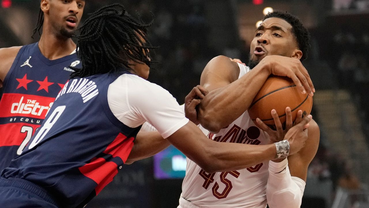 Cleveland Cavaliers guard Donovan Mitchell (45) is defended by Washington Wizards guard Bub Carrington (8) in the first half of an NBA basketball game, Friday, Dec. 13, 2024, in Cleveland.