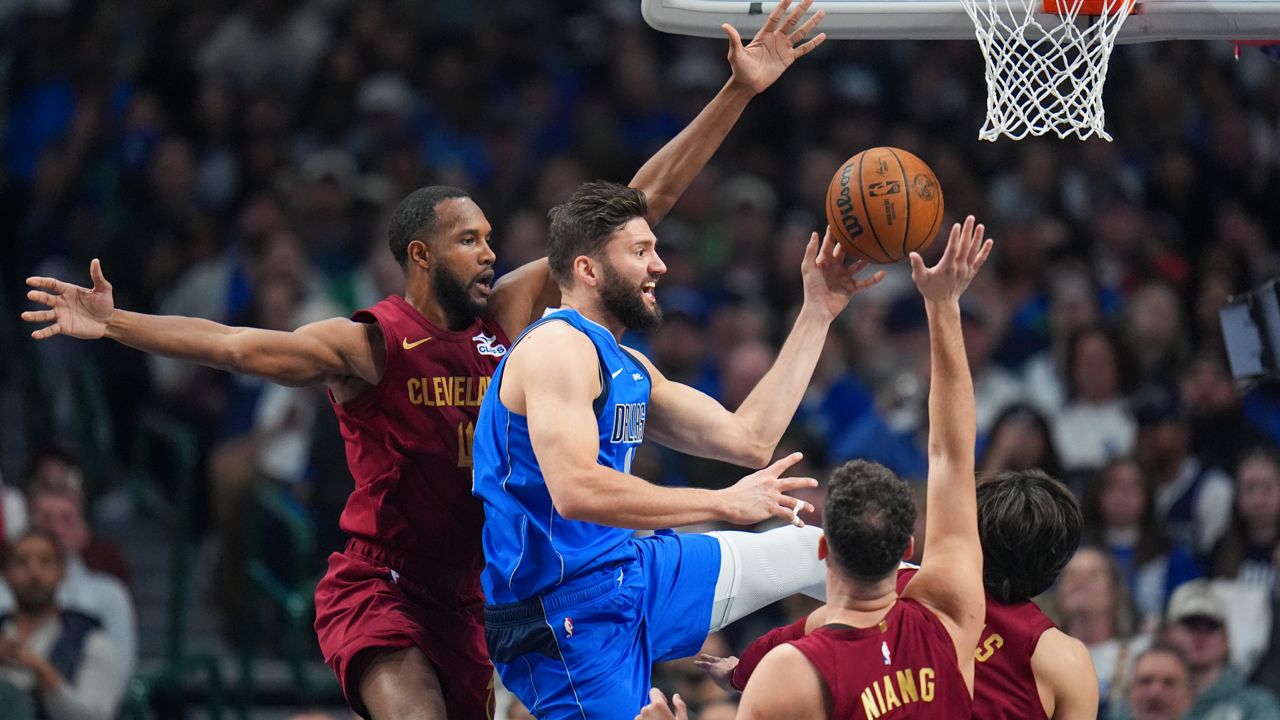 Dallas Mavericks forward Maxi Kleber, center, makes a pass as Cleveland Cavaliers forward Evan Mobley, left, and teammates defend during the first half of an NBA basketball game, Friday, Jan. 3, 2025, in Dallas.