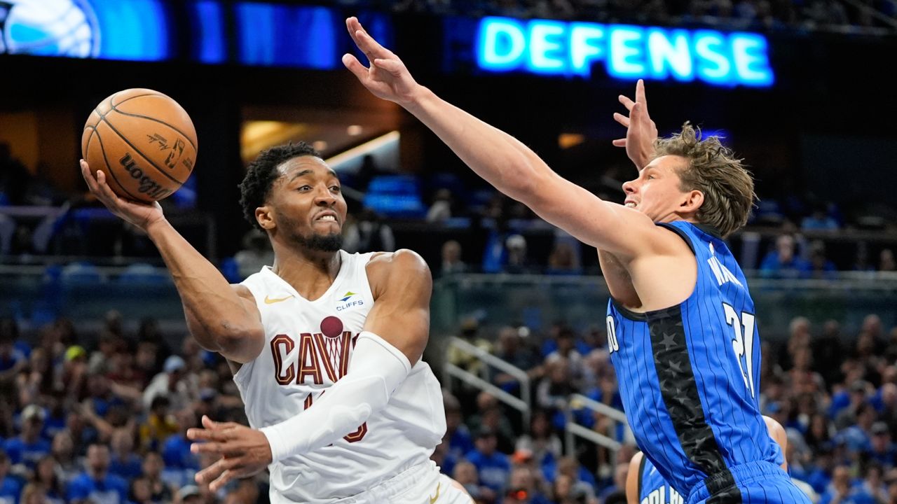 Cavaliers guard Donovan Mitchell (left) passes the basketball around Magic center Moe Wagner during Game 4 on Saturday, April 27, 2024, in Orlando, Fla. (AP Photo/John Raoux)