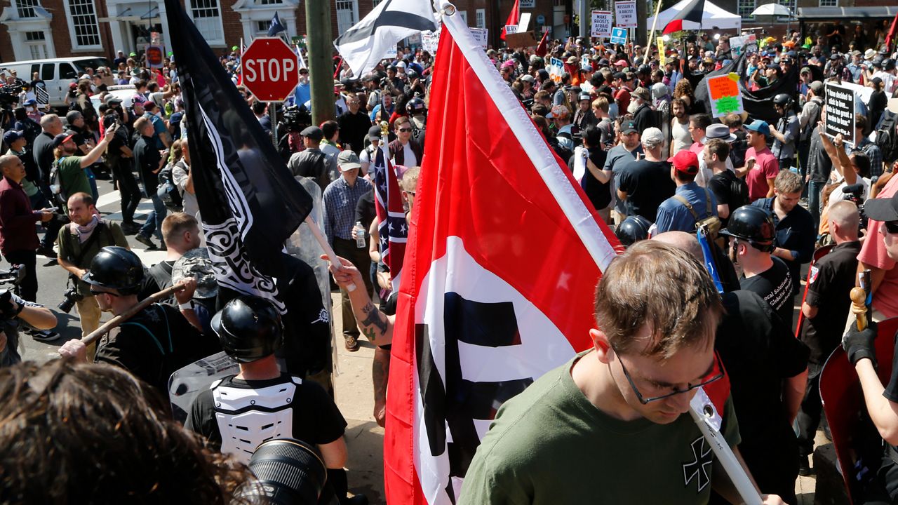 This Saturday, Aug. 12, 2017 image shows a white supremacist carrying a Nazi flag into the entrance to Emancipation Park in Charlottesville, Va. during the deadly "Unite the Right" white supremacist rally. (AP Photo/Steve Helber)