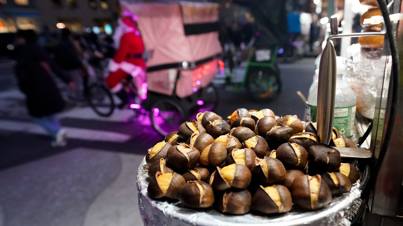 Chestnuts are displayed at a food vendor as a person dressed as Santa Claus offers rides, Thursday, Dec. 12, 2024, in New York. (AP Photo/Alyssa Goodman)