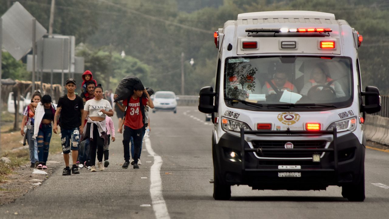 An ambulance drives past migrants walking to Huehuetan, Chiapas state, Mexico, Monday, April 24, 2023. (AP Photo/Edgar H. Clemente)