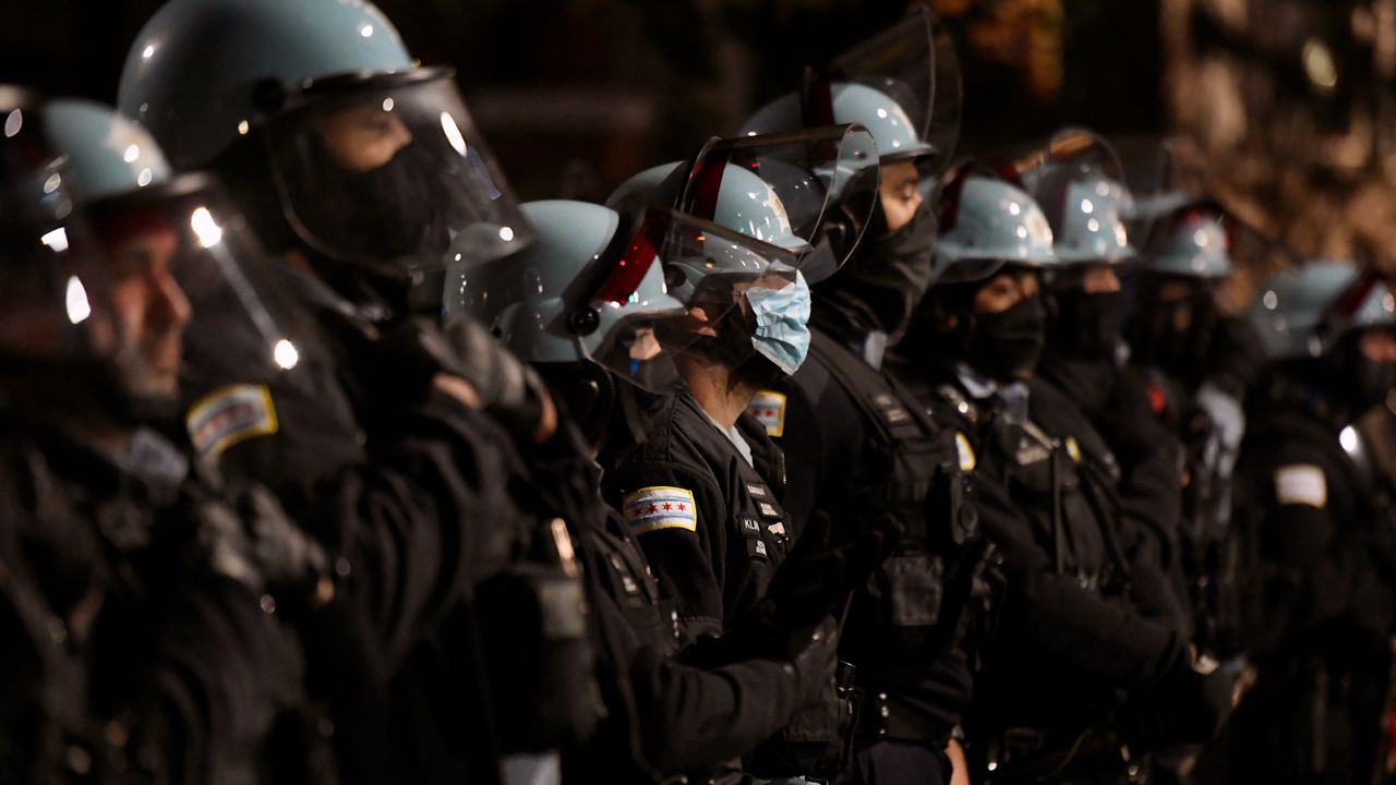 Chicago Police officers look on near Chicago Mayor Lori Lightfoot's home as people protest the March 29th shooting and killing of 13 year-old Adam Toledo by a Chicago Police officer Friday, April 16, 2021, in Chicago. (AP Photo/Paul Beaty)