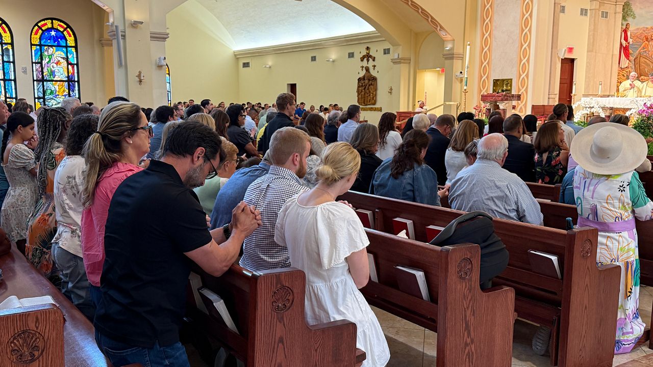 People at St. James Catholic Church pray during 9 a.m. service on Sunday.