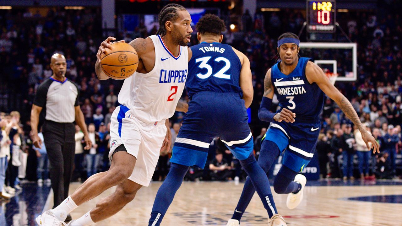 Los Angeles Clippers forward Kawhi Leonard (2) drives to the basket around Minnesota Timberwolves center Karl-Anthony Towns (32) and forward Jaden McDaniels (3) during the first half of an NBA basketball game, Sunday, Jan. 14, 2024, in Minneapolis, Minn. (AP Photo/Bailey Hillesheim)