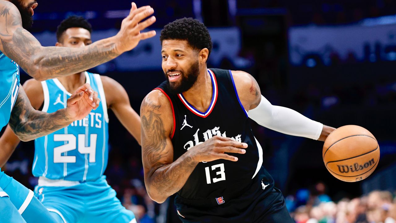 Los Angeles Clippers forward Paul George (13) drives into Charlotte Hornets center Nick Richards, left, as forward Brandon Miller looks on during the first half of an NBA basketball game in Charlotte, N.C., Sunday, March 31, 2024. (AP Photo/Nell Redmond)