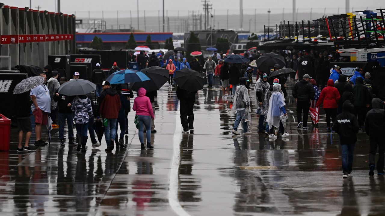 Race fans walk through the garage area while rain causes a delay to a NASCAR Cup Series auto race at Charlotte Motor Speedway Sunday, May 28, 2023, in Concord, N.C. (AP Photo/Matt Kelley)