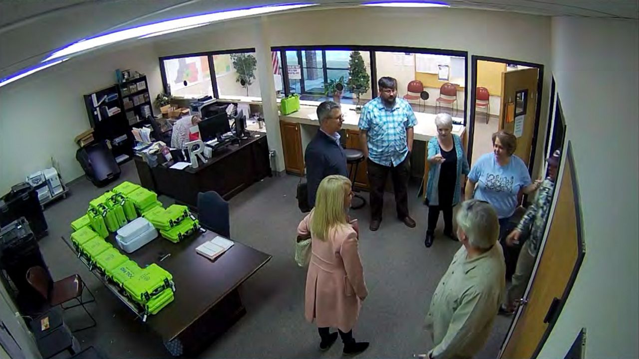 This Jan. 7, 2021, image taken from Coffee County, Ga., security video, appears to show Cathy Latham (center, long turquoise top), introducing members of a computer forensic team to local election officials. Latham was the county Republican Party chair at the time. The computer forensics team was at the county elections office in Douglas, Ga., to make copies of voting equipment in an effort that documents show was arranged by attorney Sidney Powell and others allied with then-President Donald Trump. (Coffee County, Georgia via AP)