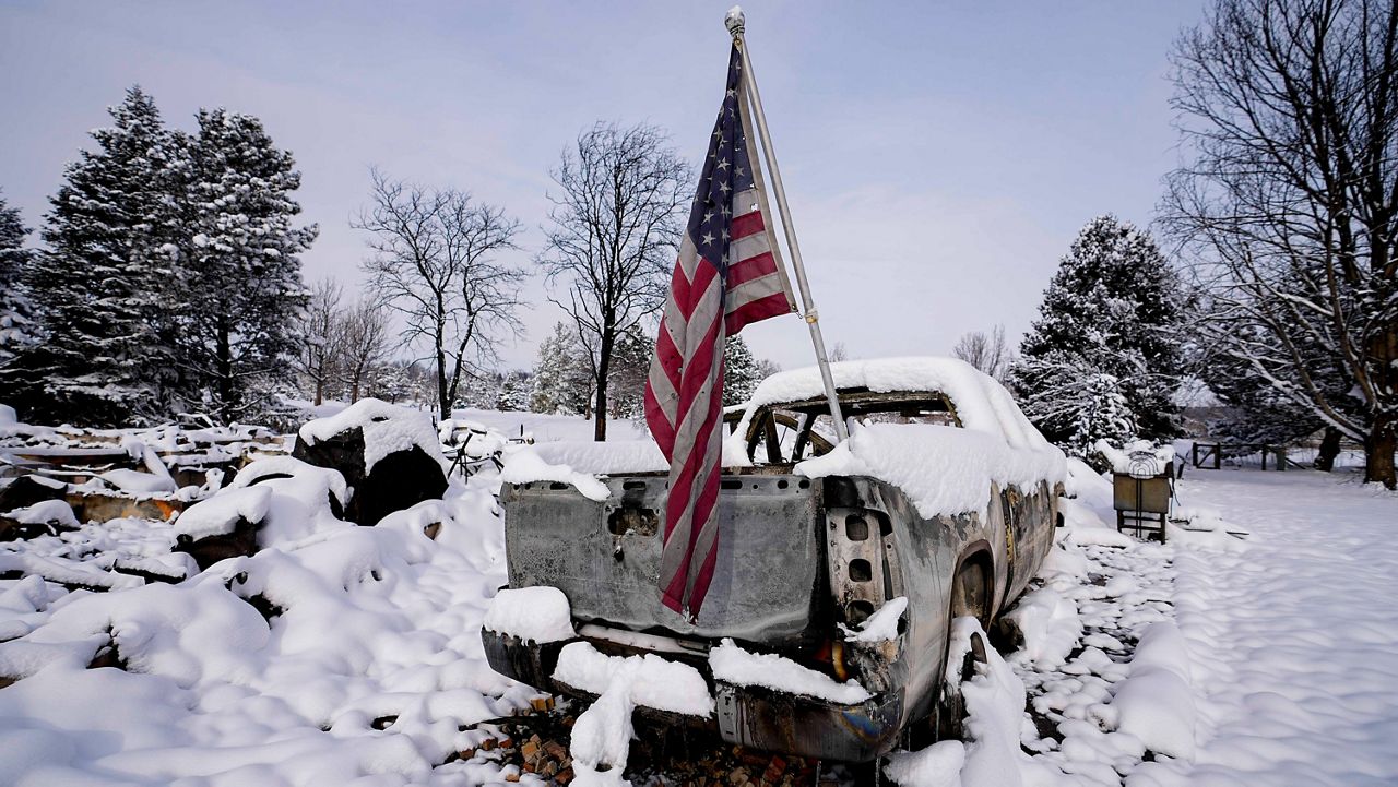 A soot covered American flag waves from the bed of a burned out pickup truck after the Marshall Wildfire Saturday, Jan. 1, 2022, in Louisville, Colo. (AP/Jack Dempsey)