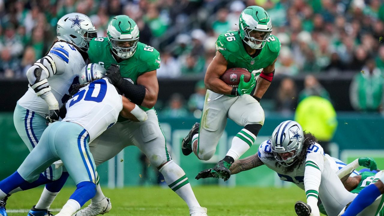 Philadelphia Eagles running back Saquon Barkley, center, leaps as Dallas Cowboys linebacker Marist Liufau tries to trip him up during the second half of an NFL football game, Sunday, Dec. 29, 2024, in Philadelphia. (AP Photo/Matt Slocum)