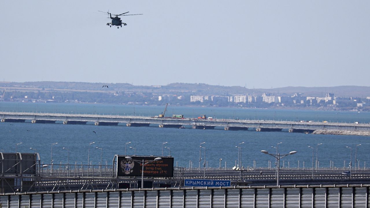 A Russian military helicopter flies over damaged parts of an automobile link of the Crimean Bridge connecting Russian mainland and Crimean peninsula over the Kerch Strait not far from Kerch, Crimea, on Monday, July 17, 2023. (AP Photo)