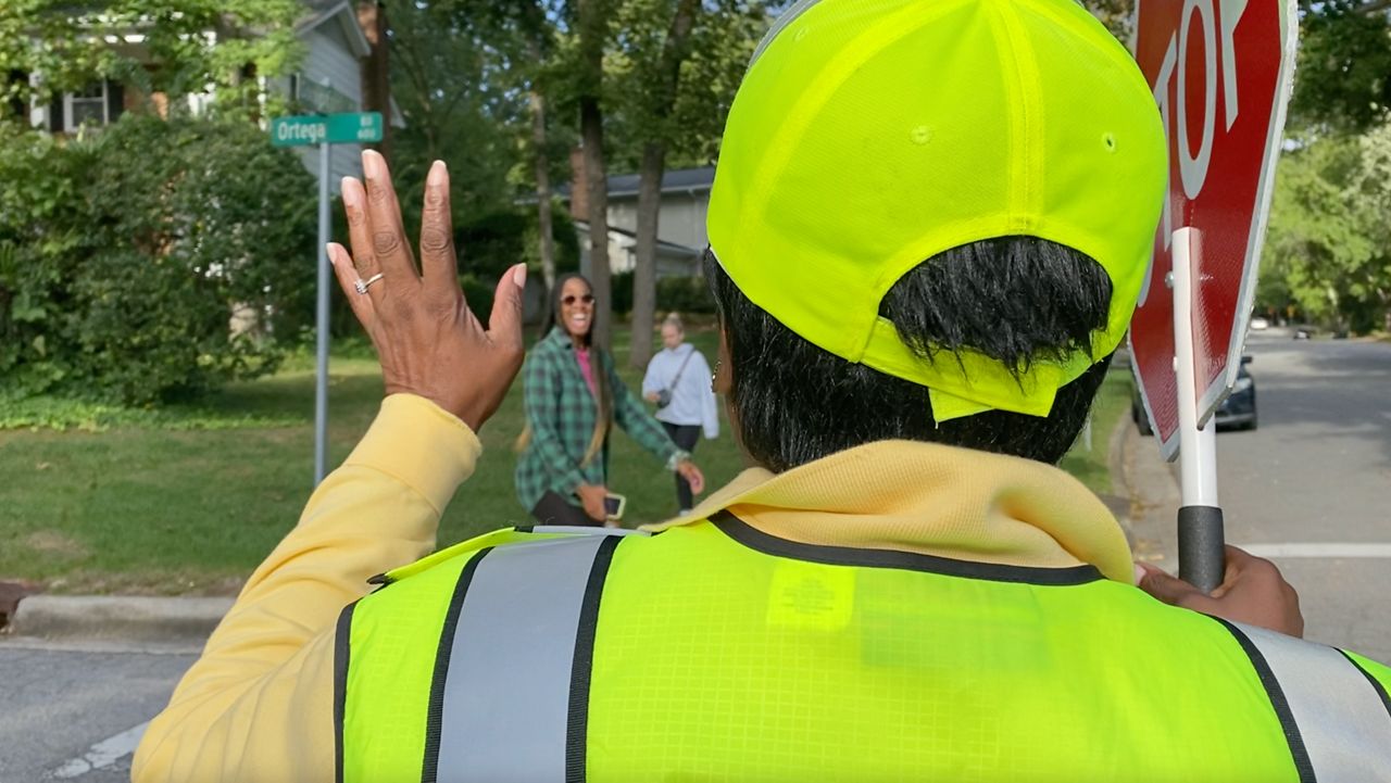 Teressa Gill, a Raleigh crossing guard, waves at a pedestrian.