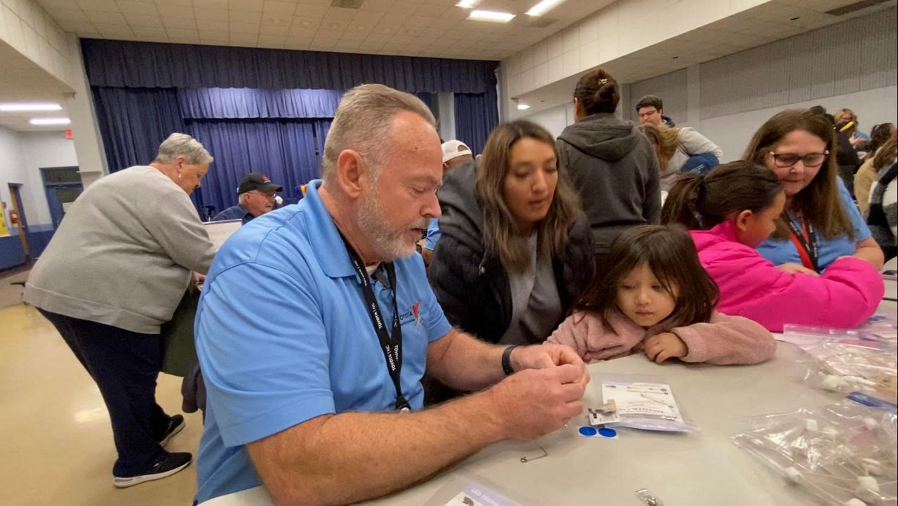 Curt Wagner, a new Toyota employee, shows a student at Liberty Elementary School how to create a name tag. (Spectrum News 1/Zyneria Byrd)