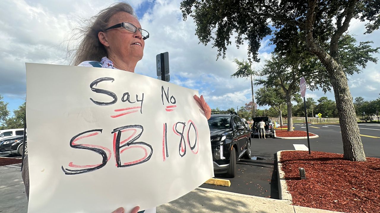 As she waits to see how the city commission would vote on a residential development moratorium, Deltona resident Stephanie Cox displays her disdain for a new Florida law in front of Deltona City Hall Monday with a sign saying 