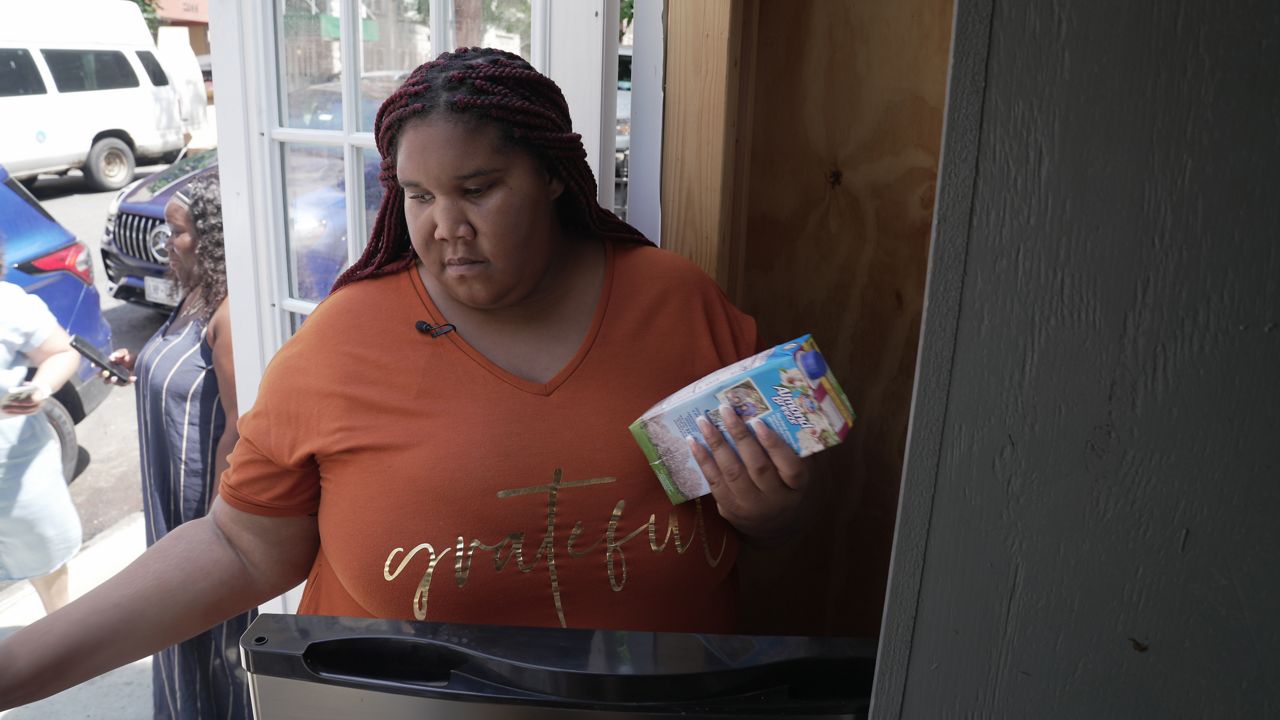 Shaida Gray fills a community fridge in Bedford Park. (Spectrum News NY1/Chelsea Katz)