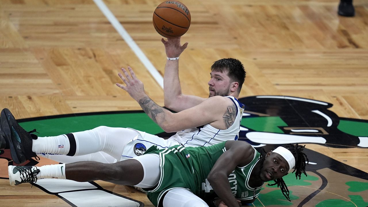 Dallas Mavericks guard Luka Doncic, top, and Boston Celtics guard Jrue Holiday, bottom, land on the parquet as they vie for the ball during the first half of Game 5 of the NBA basketball finals, Monday, June 17, 2024, in Boston. (AP Photo/Charles Krupa)