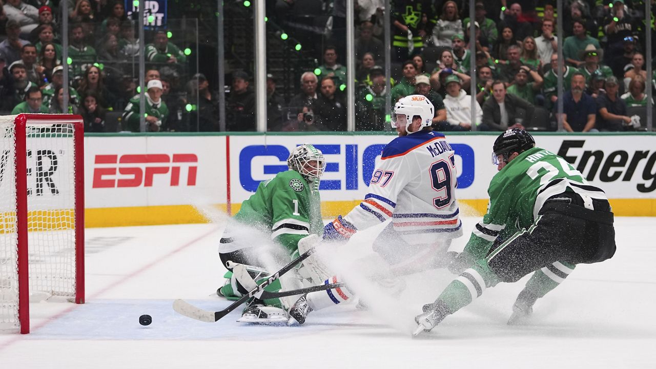 Edmonton Oilers center Connor McDavid (97) scores against Dallas Stars goaltender Casey DeSmith (1) and center Roope Hintz (24) during the second period of Game 5 of the Western Conference finals in the NHL hockey Stanley Cup playoffs, Thursday, May 29, 2025, in Dallas. (AP Photo/Julio Cortez)