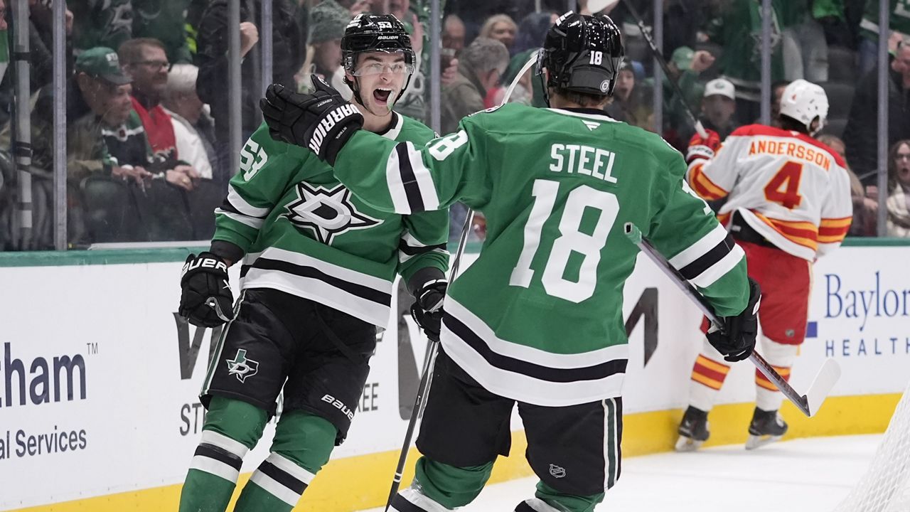 Dallas Stars center Wyatt Johnston (53) celebrates with teammate Sam Steel (18) after his goal against Calgary Flames defenseman Rasmus Andersson (4) during the first period of an NHL hockey game Sunday, Dec. 8, 2024, in Dallas. (AP Photo/LM Otero)