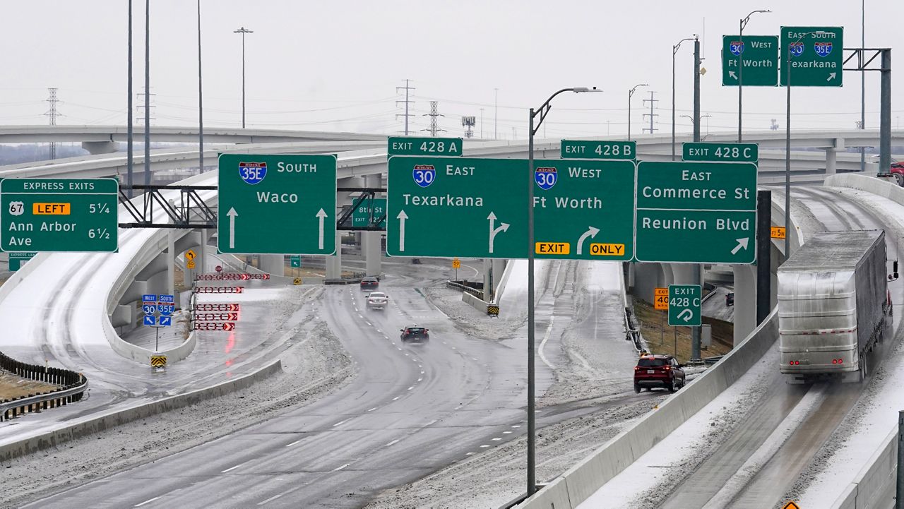 A road sign in yellow warns drivers of icy road conditions at a busy IH 30 and IH 35 interchange, Wednesday, Feb. 1, 2023, in Dallas. (AP Photo/Tony Gutierrez)