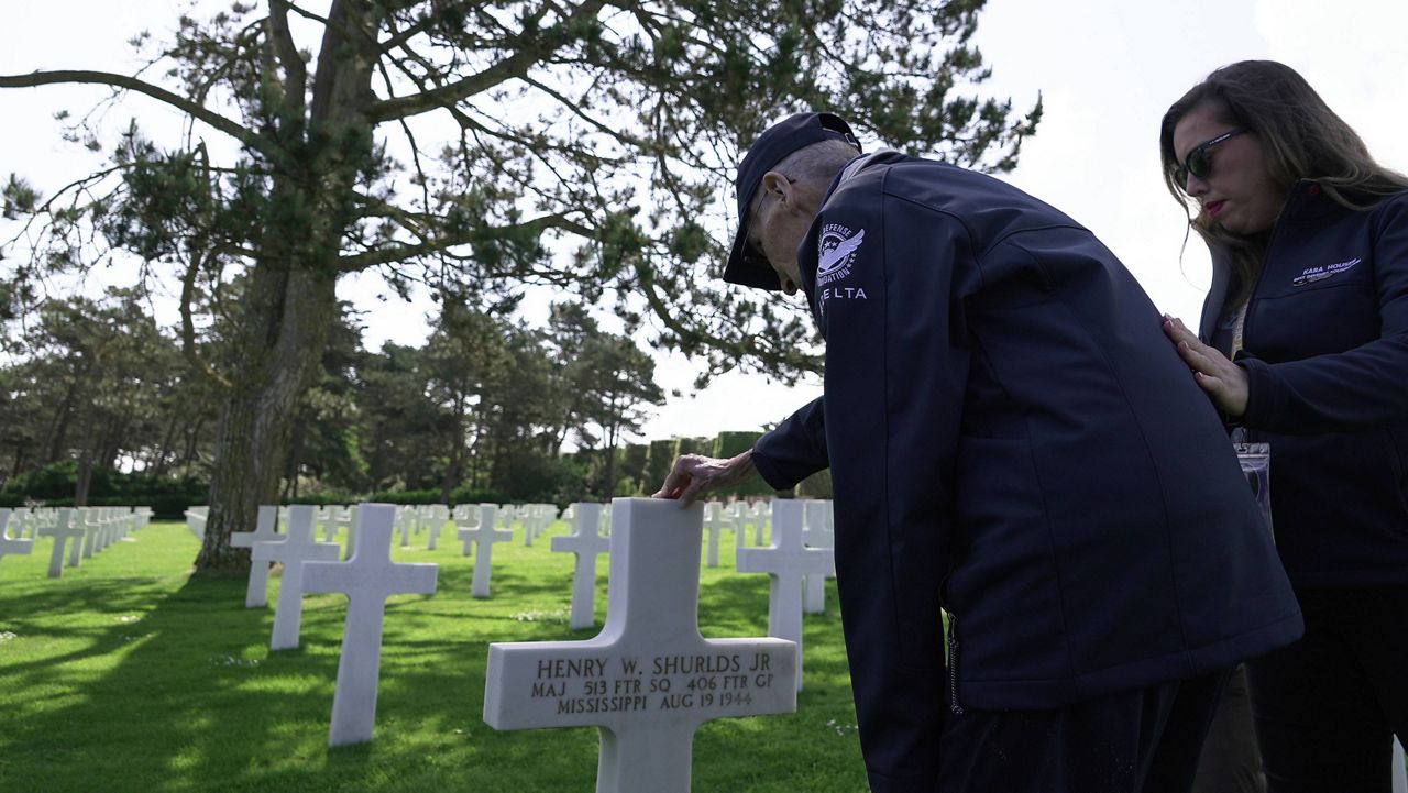 Wally King, a 101-year-old former U.S. fighter pilot who flew 75 combat missions in World War II, and his granddaughter Kara Houser pay their respects Monday, June 2, 2025 in Colleville-sur-Mer, at the Normandy American Cemetery grave of Henry Shurlds Jr., who flew P-47 "Thunderbolt" fighters like King and was shot down and killed on Aug. 19, 1944, above the town of Verneuil-sur-Seine, northwest of Paris. (AP Photo/John Leicester).
