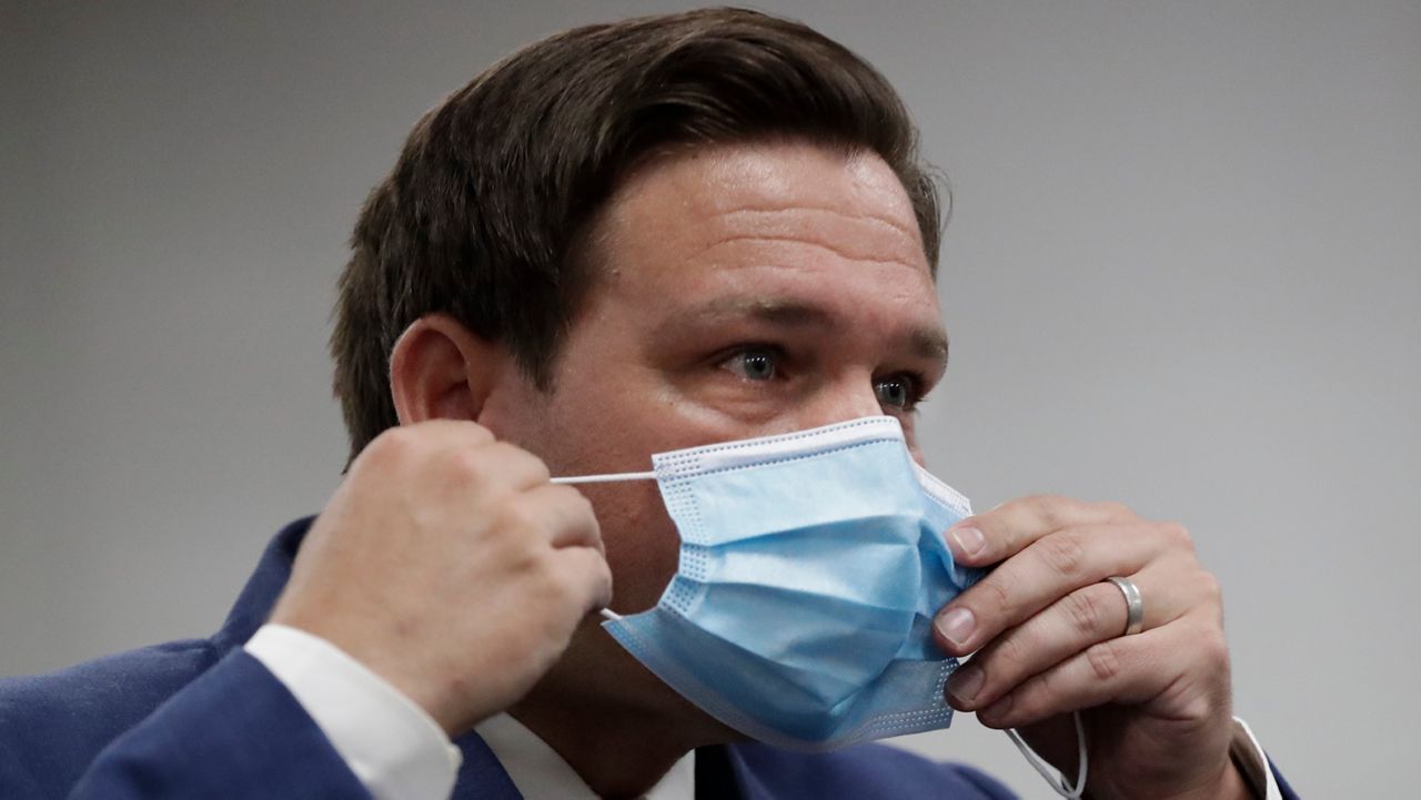 Florida Gov. Ron DeSantis puts on his mask as he leaves a news conference at Jackson Memorial Hospital. (Wilfredo Lee/AP)