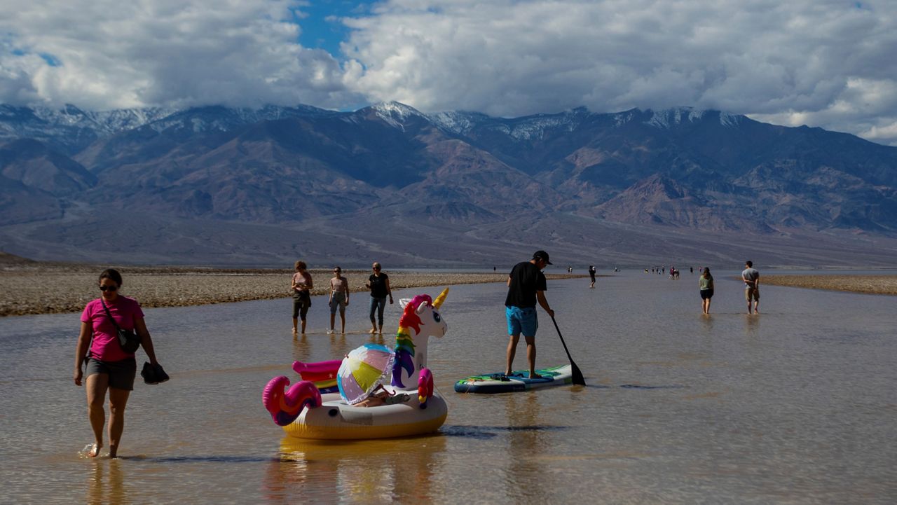 A paddle boarder tows an inflatable unicorn on a temporary lake in Death Valley on Thursday, Feb. 23, 2024, in Death Valley National Park, Calif. (AP Photo/Ty ONeil)