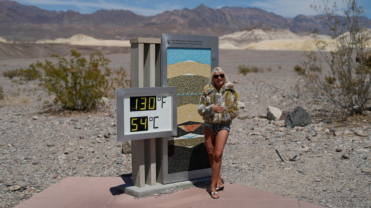 A woman poses by a thermometer, Sunday, July 16, 2023, in Death Valley National Park, Calif. (AP Photo/John Locher)