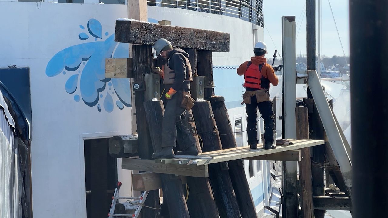 DiMillos: Workers repair the wooden pilings outside DiMillo's On the Water on Portland's waterfront Thursday. The restaurant itself weathered historic high storm surges on Saturday, but exterior objects such as the pilings needed to be fixed. (Spectrum News/Sean Murphy)