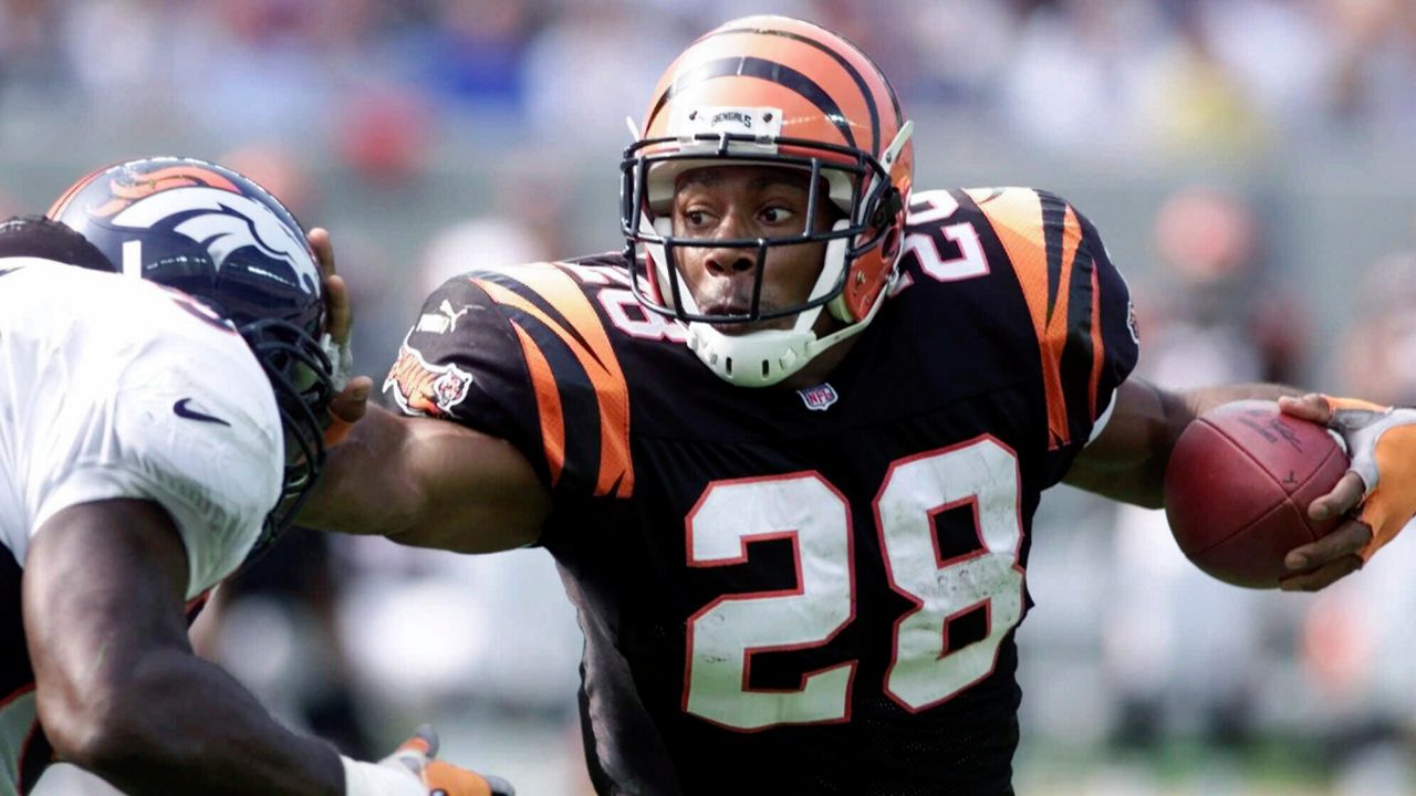 Cincinnati Bengals running back Corey Dillon (28) pushes away Denver Broncos defender Al Wilson, left, in the first half Sunday, Oct. 22, 2000, in Cincinnati.