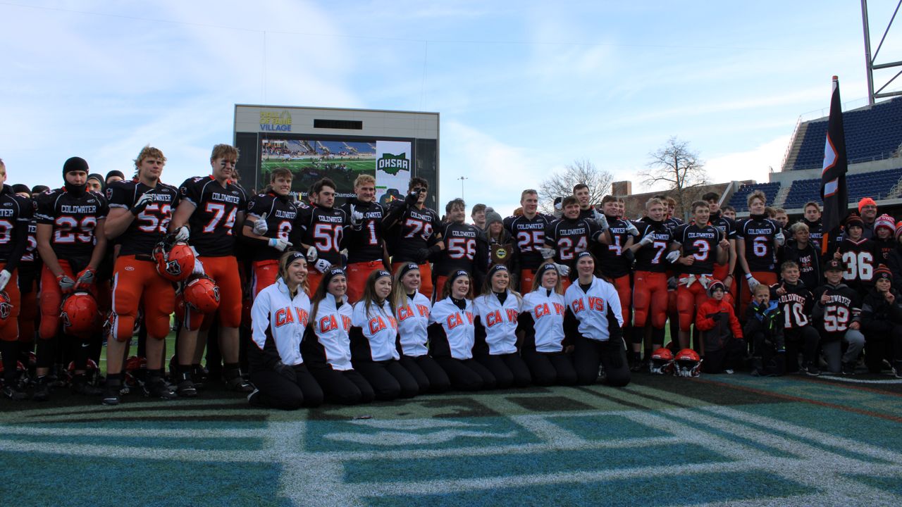 The Coldwater High School football team and cheerleaders stand with the state championship trophy after the OHSAA Division VI football state championship game at Tom Benson Hall of Fame Stadium on Saturday.