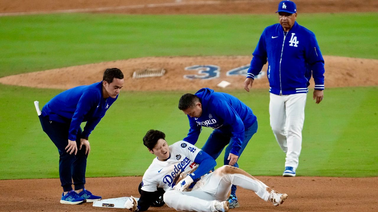 Los Angeles Dodgers' Shohei Ohtani, center, reacts after being injured while trying to steal second base against the New York Yankees during the seventh inning in Game 2 of the baseball World Series, Saturday, Oct. 26, 2024, in Los Angeles. (AP Photo/Julio Cortez)