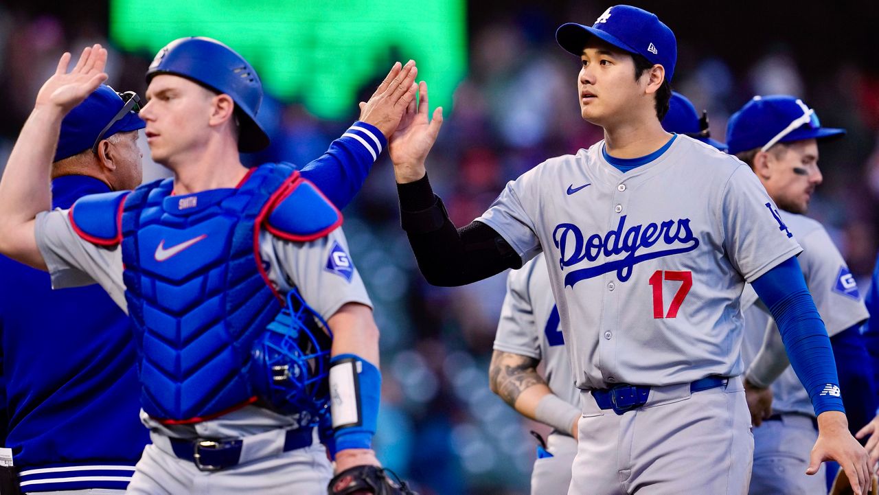 Los Angeles Dodgers' Shohei Ohtani, right, celebrates with manager Dave Roberts, back left, after the team's victory over the San Francisco Giants in a baseball game Saturday, June 29, 2024, in San Francisco. (AP Photo/Godofredo A. Vásquez)