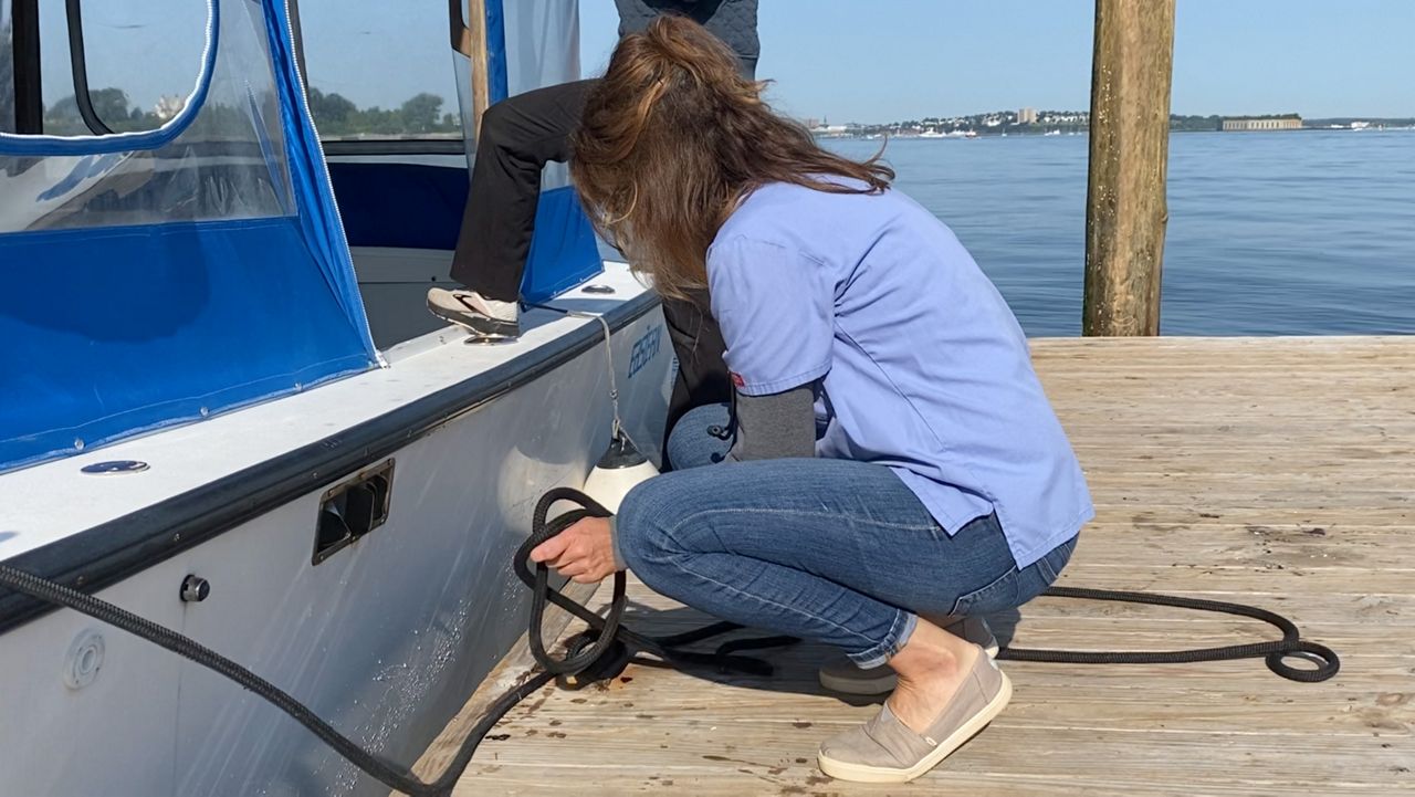 Dr. Kate Domenico, owner of Island Veterinary Services, secures a line on her converted lobster boat at the dock at Peaks Island Thursday. Domenico often travels to the islands in Casco Bay twice a week bringing basic veterinary care to pets and other animals. (Spectrum News/Sean Murphy)