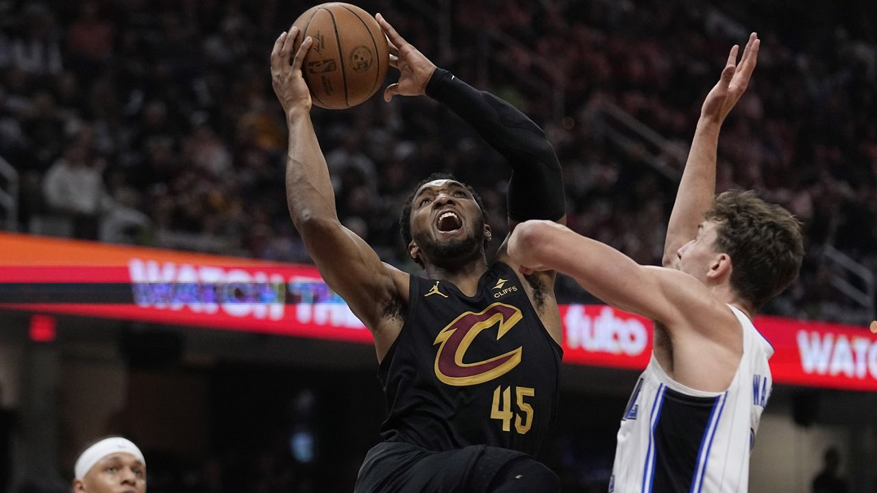 Cleveland Cavaliers guard Donovan Mitchell (45) shoots between Orlando Magic forward Paolo Banchero (5) and forward Franz Wagner, right, in the first half of Game 7 of an NBA basketball first-round playoff series Sunday, May 5, 2024, in Cleveland. (AP Photo/Sue Ogrocki)