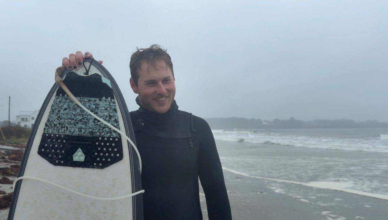 Canadian surfer Douglas Biron with his surfboard on Higgins Beach in Scarborough on Sept. 28. Biron traveled from Québec City to Scarborough to surf the waves caused by the nor’easter that hit the East Coast over the weekend. (Spectrum News/Jules Walkup)