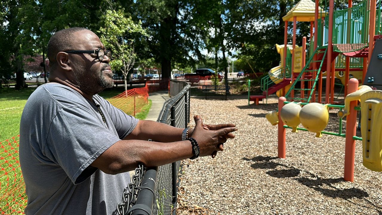 Joseph Blue stands along a fence at the Walltown Park playground, which has been closed off while soil is being tested.