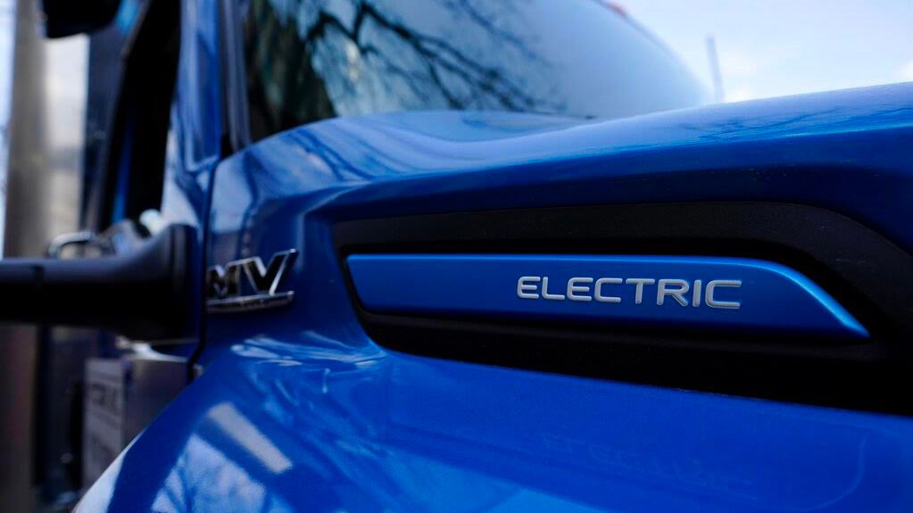 The hood of a blue EV Heavy-duty truck with a badge showing the word 'Electric'.