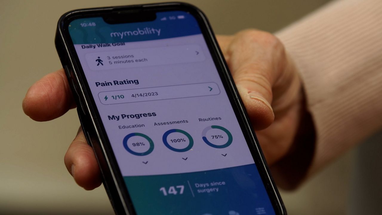 Patient Barbara Girz shows Spectrum News the phone app she uses to monitor her knee replacement recovery.