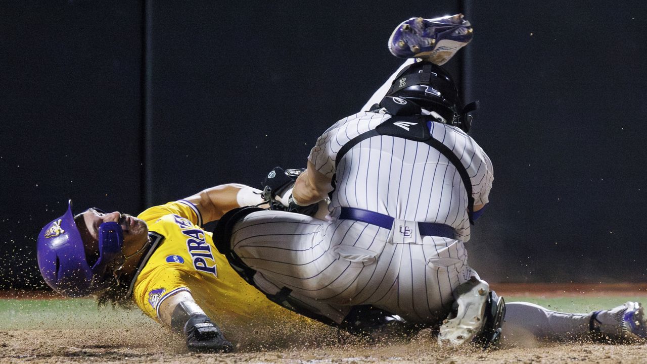 East Carolina's Jacob Jenkins-Cowart, left, scores a run past Evansville's Brendan Hord, right, during an NCAA regional baseball game on Sunday, June 2, 2024, in Greenville, N.C. (AP Photo/Ben McKeown)