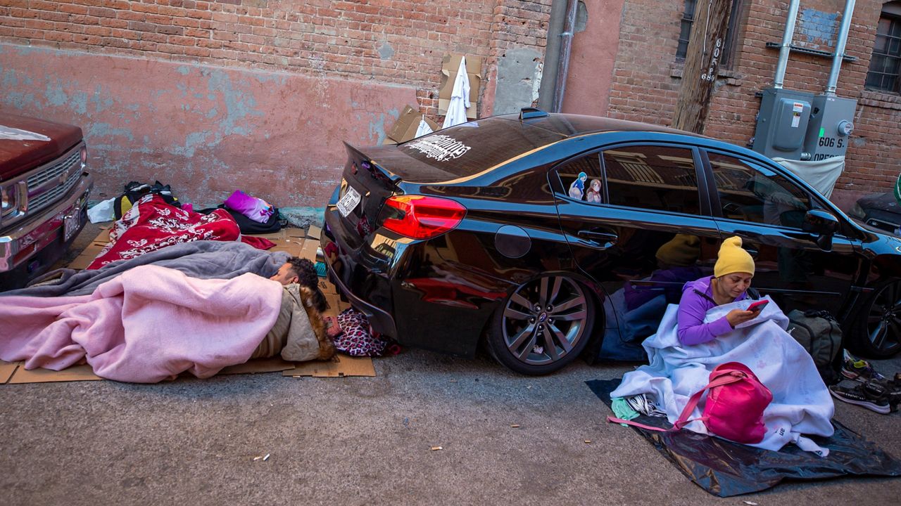Migrants wake up while camping on a street in downtown El Paso, Texas, Sunday, April 30, 2023. The border city declared a state of emergency on Monday, May 1 in response to the large numbers of migrants already camping on the streets, before the Title 42 expires on May 11. (AP Photo/Andres Leighton)