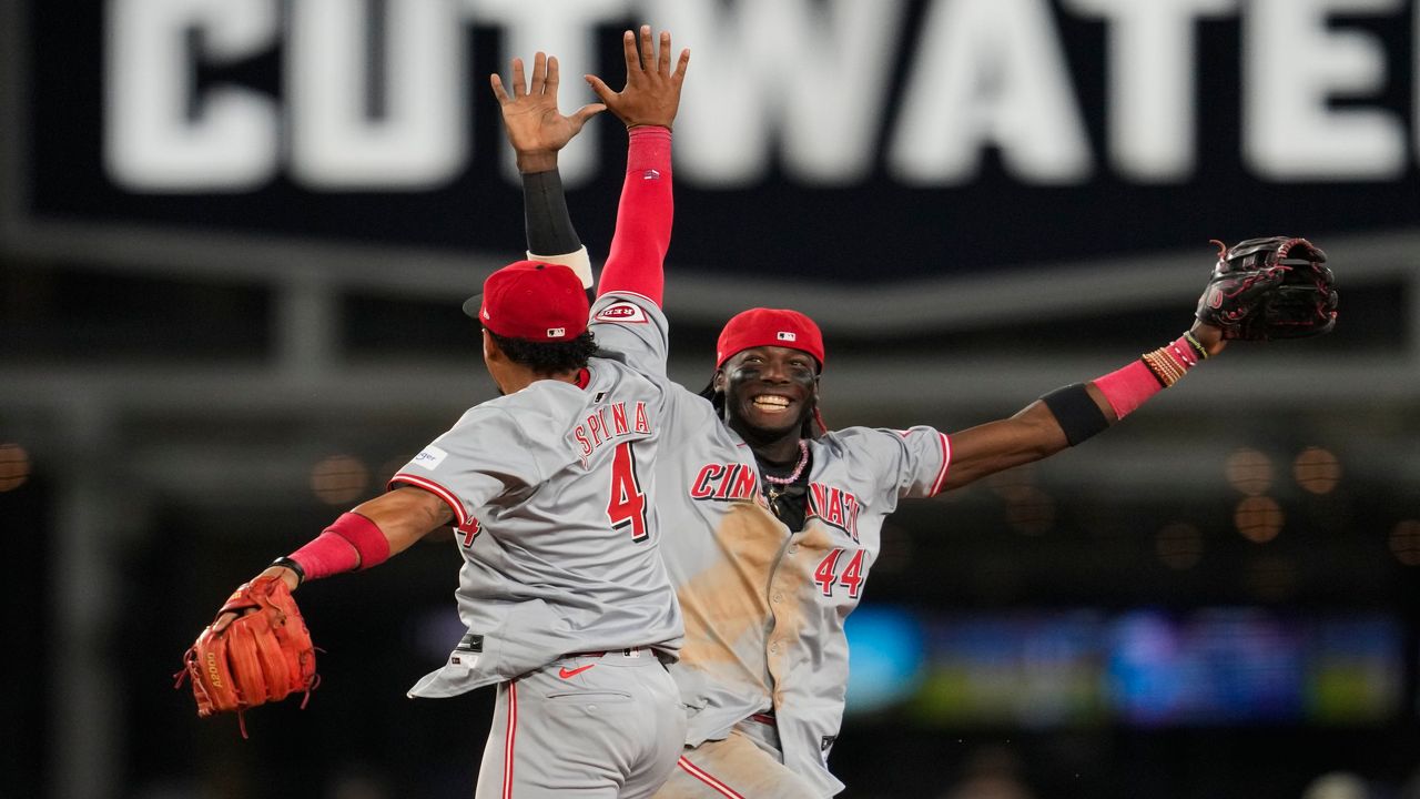 Cincinnati Reds second baseman Santiago Espinal (4) and shortstop Elly De La Cruz (44) celebrate after winning 7-2 over the Los Angeles Dodgers in a baseball game in Los Angeles, Thursday, May 16, 2024. (AP Photo/Ashley Landis)
