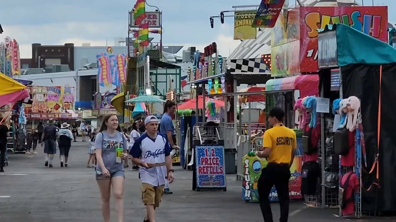 erie county fairgoers walk through corridor of food and game tents