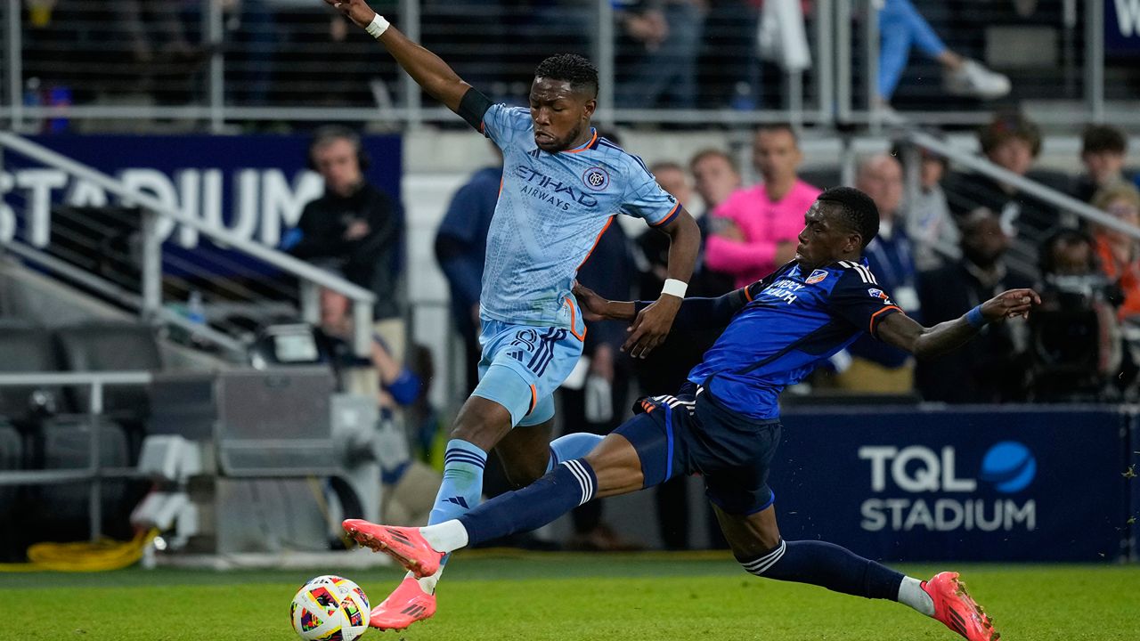 New York City FC midfielder Andrés Perea, left, and FC Cincinnati defender Teenage Hadebe right, fight for the ball during the second half of a first-round soccer match of the MLS Cup playoffs, Monday, Oct. 28, 2024, in Cincinnati. (AP Photo/Carolyn Kaster)