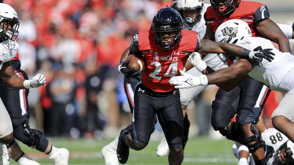 Cincinnati running back Jerome Ford (24) carries the ball as he breaks a tackle against UCF linebacker Jeremiah Jean-Baptiste, right, during the first half of an NCAA college football game, Saturday, Oct. 16, 2021, in Cincinnati. (AP Photo/Aaron Doster)