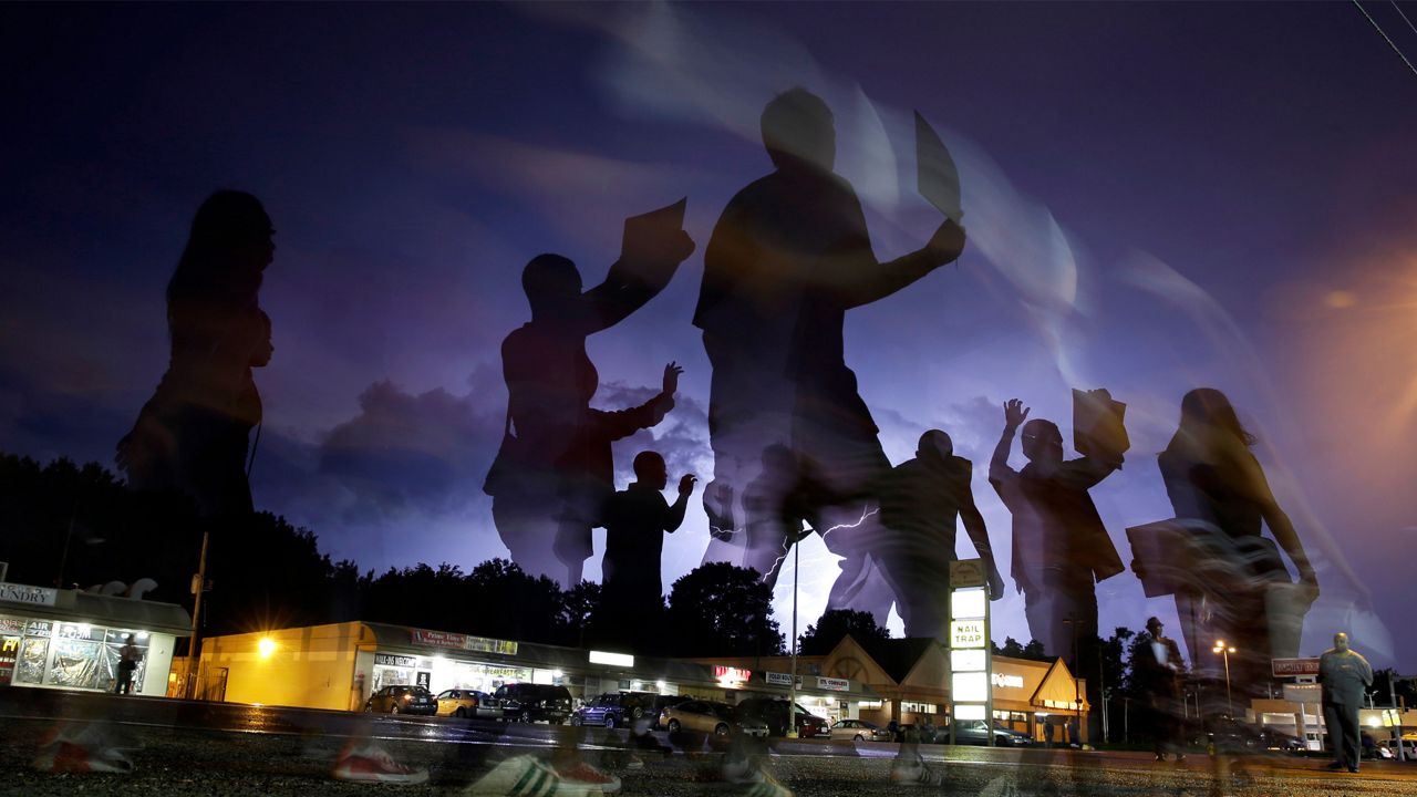 Protesters march in the street as lightning flashes in the distance in Ferguson, Mo., Aug. 20, 2014, following the shooting of Michael Brown, an unarmed Black teen, in the St. Louis suburb on Aug. 9. A legal nonprofit announced Tuesday, Feb. 27, 2024 that Ferguson has agreed to pay $4.5 million to settle a so-called debtors' prison lawsuit that accused the city of making money for its coffers over fines and court costs. (AP Photo/Jeff Roberson, File)