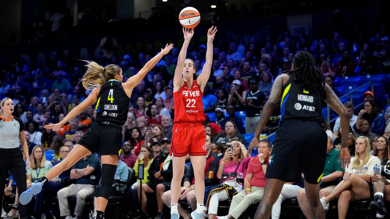 Indiana Fever guard Caitlin Clark (22) shoots as Dallas Wings' Jacy Sheldon (4) and Natasha Howard, right, defend in the first half of a WNBA basketball game Sunday, Sept. 1, 2024, in Arlington, Texas. (AP Photo/Tony Gutierrez)