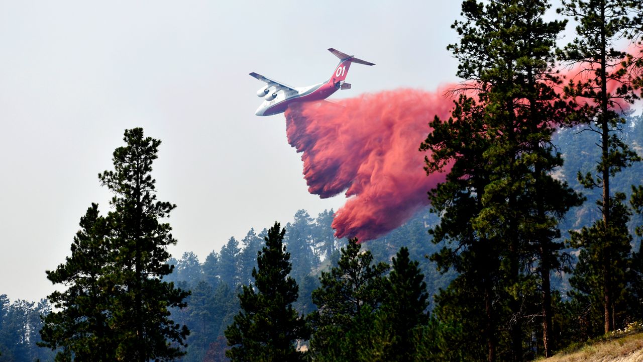 An aircraft drops fire retardant to slow the spread of the Richard Spring fire, east of Lame Deer, Mont., on Aug. 11, 2021. A legal dispute in Montana could drastically curb the government’s use of aerial fire retardant to combat wildfires. Environmentalists have sued the U.S. Forest Service over waterways being polluted with the potentially toxic red slurry that’s dropped from aircraft. Forest Service officials have acknowledged more than 200 cases of retardant landing in water. (AP Photo/Matthew Brown, File)