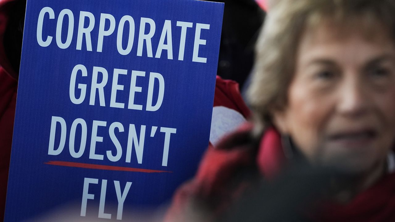 A flight attendant holds a sign during a demonstation at O'Hare International Airport in Chicago on Tuesday. On the same day, dozens of local flight attendants picked at Honolulu's airport as part of a "worldwide day of action" in hopes of getting higher wages as contracts are negotiated with airlines. (AP Photo/Nam Y. Huh)