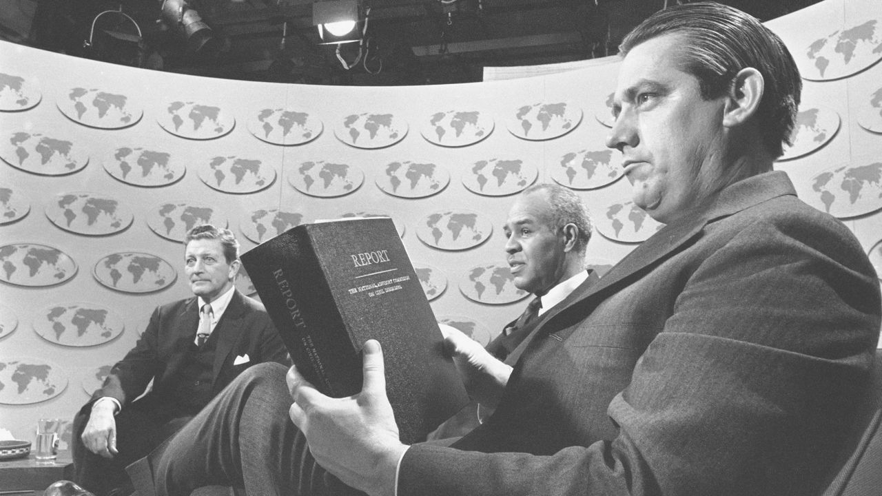 Sen. Fred R. Harris (D-Okla.), holds a copy of the report of the National Advisory Commission on Civil Disorders as he and two other members of the commission discuss the study on the television-radio program "Issues and Answers," in Washington, March 3, 1968. (AP Photo/Bob Daugherty, File)