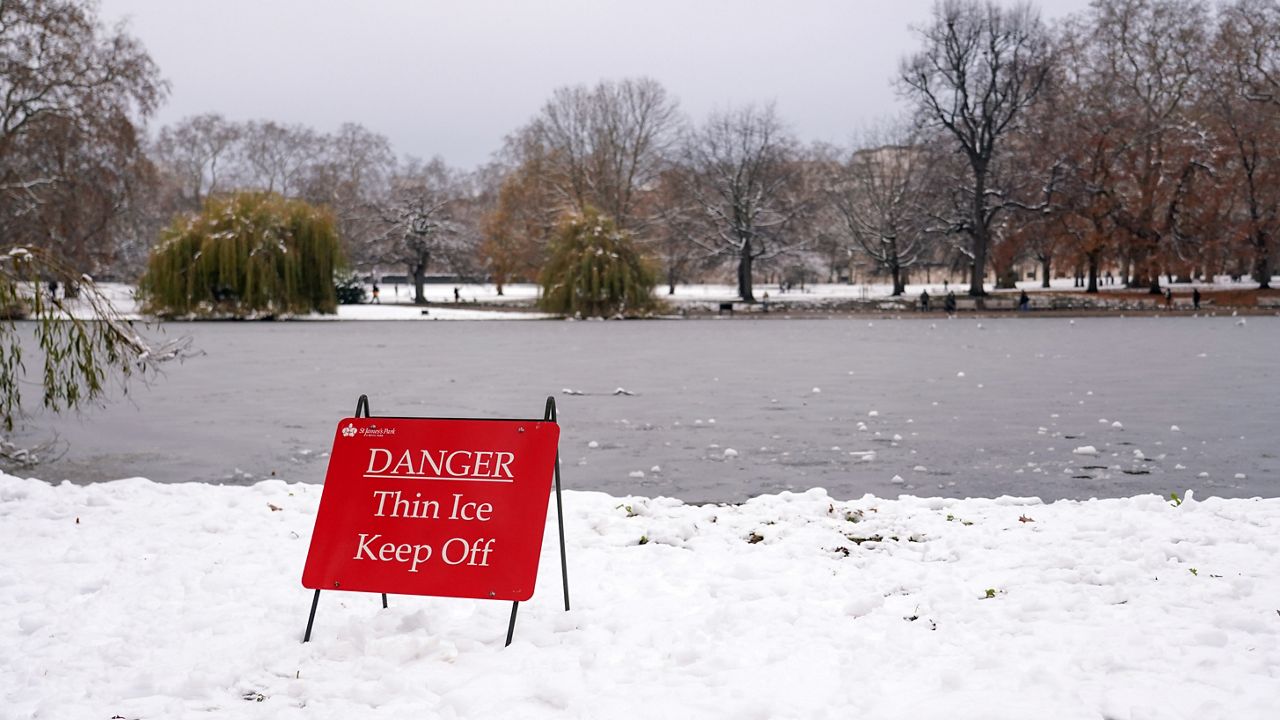 A warning sign is seen in St James's Park, as the lake is covered with a layer of ice, in London, Monday, Dec. 12, 2022. 